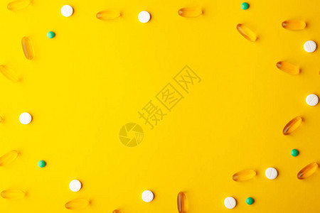 许多分散的药物维生素药丸鱼油软胶囊药片在治疗期间放置在黄色表面食品膳食补充剂中心复制图片