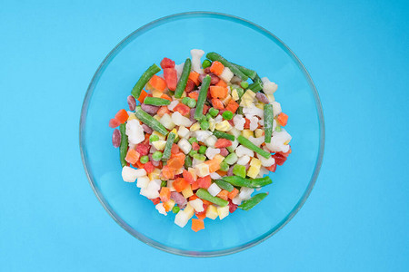 蓝色背景的玻璃碗中碎冰冻蔬菜水平方向从上面查看info图片