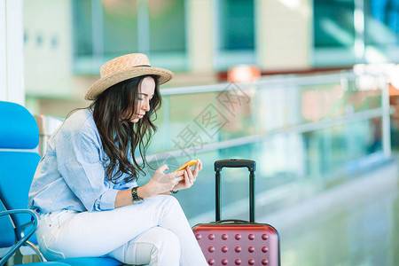 带着行李的年轻女青年在国际机场等待飞行图片