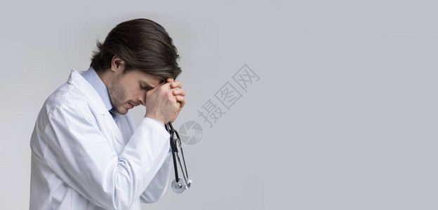 抑郁过度劳累的男医生手拿听诊器头痛绝望和无力有自由图片