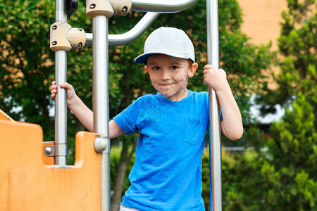 可爱的小男孩在户外操场上攀爬快乐健康的童年戴着帽子的时尚孩子童装时尚暑假孩子们在户外积极休闲快乐的男孩背景图片