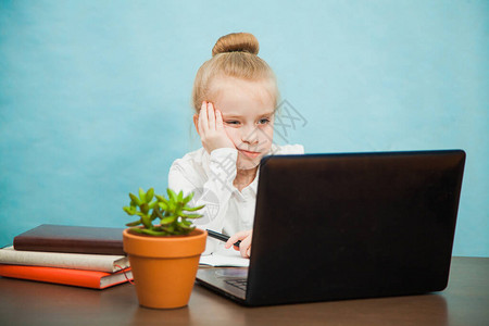 悲伤疲惫的小学生女孩通过互联网在笔记本电脑上在家上学一年级女学生