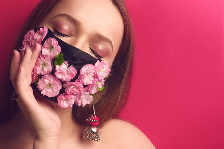 一个戴着鲜花面具的粉红色背景模特的肖像女孩吸入鲜花粉红色背景的女孩图片