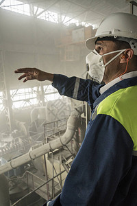 黄蓝色制服白色头盔和呼吸器的采矿工程师监督花岗岩车间的工作背景图片