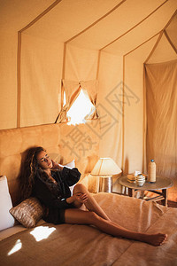 摩洛哥现代豪华露营帐篷营地内部东方女感魅力肖像在床上放松生态设计理念自然和木图片