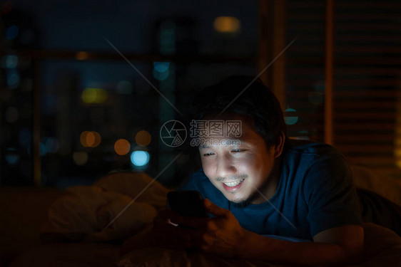 特写亚洲男人睡觉和使用智能手机进行社交网络或视频电话会议图片