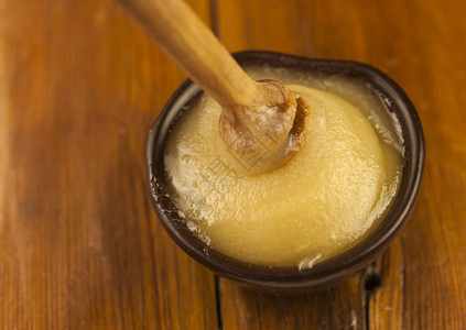 蜂蜜从泥碗中的蜂蜜勺滴下特写健康有机厚蜂蜜从木蜂蜜勺中蘸取图片