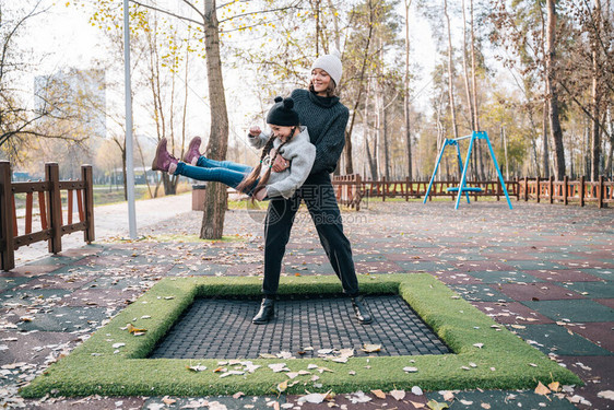 妈和女儿一起在秋天公园的蹦床上跳图片