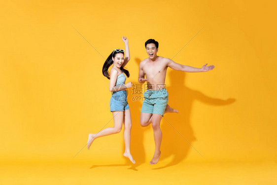 夏日沙滩临时穿衣的充满活力的亚洲快乐情侣在黄色背景图片