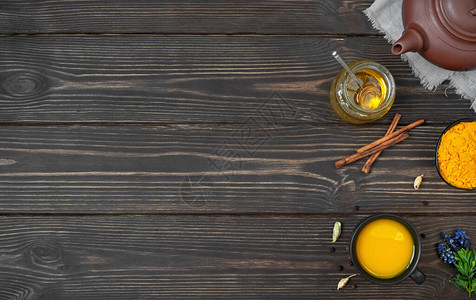 一杯凉茶姜黄和木制背景上的香料带茶的陶瓷茶壶和带磨碎姜黄的碗和制茶用的配料免疫刺激剂图片