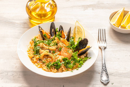 浅色木质背景盘中的海鲜烩饭意大利菜图片