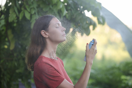 女在脸上喷洒面雾暑假背景图片