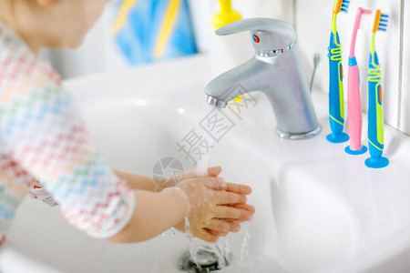 蹒跚学步的小女孩在浴室里用肥皂和水洗手的特写镜头关闭孩子学习清洁身体部位早上的卫生习惯健康的孩子在图片