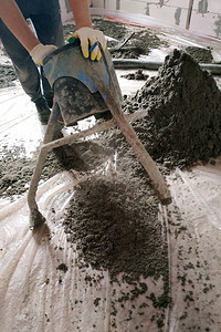 工人在地板加热上方进行沙水泥地板的铺盖图片