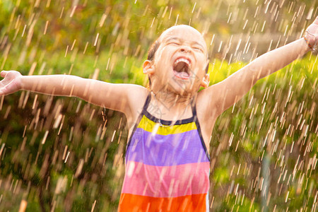 可爱的小女孩在后院的雨中玩得开心图片