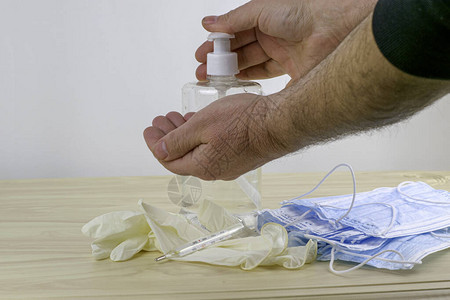 桌上摆着医用防护卫生面具橡胶手套温度计和透明瓶中的消毒剂图片