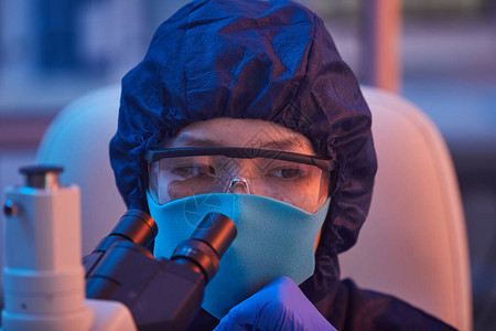 在实验室工作时通过显微镜观察保护面罩和眼镜女科学家的近身检查图片