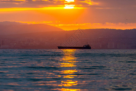 货船在金色的日落或日出时在海上航行太阳落山或升起时跨水海运大自然的和谐与美丽风景秀图片