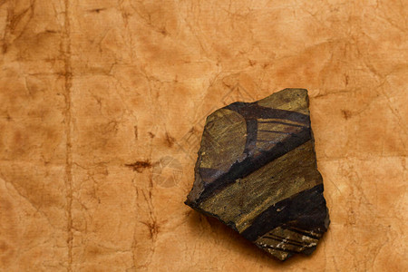 考古发现古代陶器的碎片在旧纸的背景上图片