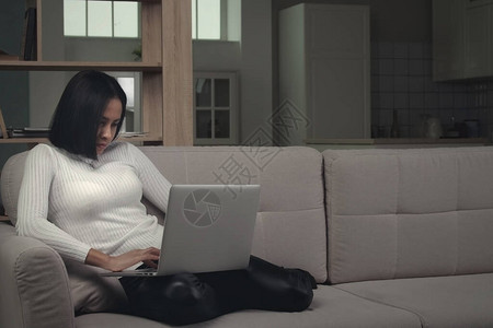 严肃的千禧一代非洲裔美国年轻女学生自由职业者在家办公室靠在沙发上使用笔记本电脑设备图片
