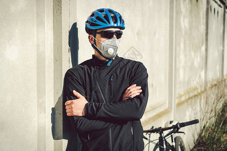 带过滤器的保护呼吸器PM25灰色混凝土墙附近的肖像男骑自行车者保护人体呼吸器官免受空气中的灰尘和悬浮颗粒图片