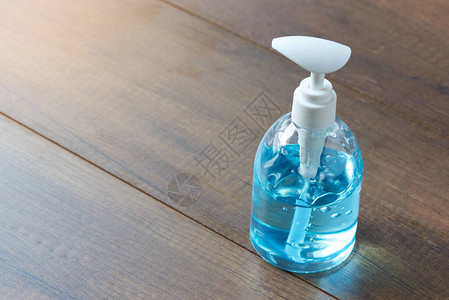 一瓶木制背景上带有蓝色酒精凝胶的洗手液酒精凝胶可防止病图片