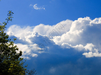 美丽的白云在蔚蓝的天空中阳光穿过的棉质积雨云可以宣布下雨的天气场景图片