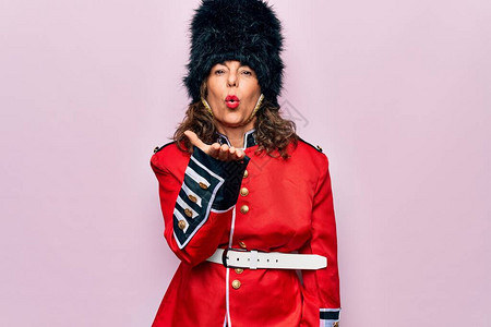 中年美丽的威尔士守卫妇女穿着粉红色背景的传统制服图片