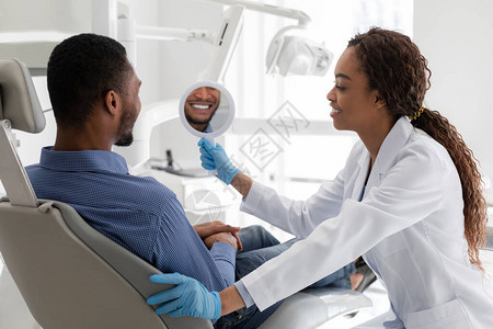 非洲牙医和病人在白化手术后检查镜面微笑的非洲牙医和病图片