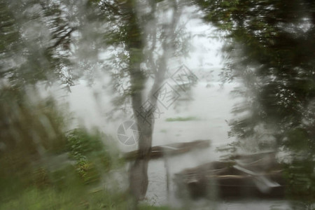 雨天透过家庭窗户看到的湖泊和船只景观图片