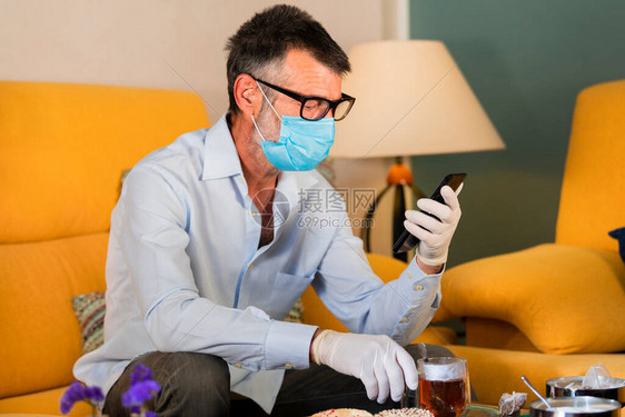 带面罩和手套回家的男子在医疗上喝杯茶图片
