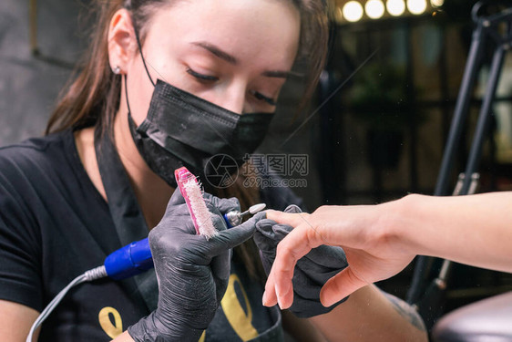 用于去除凝胶抛光的硬件铣刀特写镜头在美容院的设备修指甲美甲师用电动指甲钻去除客户指甲上的旧凝胶更图片