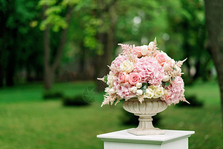 一束美丽的花朵在一块花瓶里站在绿背景的柱子上婚礼的装图片
