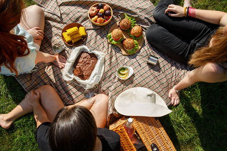 在绿色草坪上用汉堡玉米布朗尼水果和柠檬水野餐图片