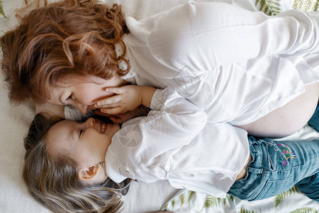 母亲的女儿时刻孕妇与女儿一起躺在床背景