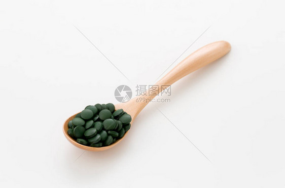绿药丸白底的木制勺子里的斯图片