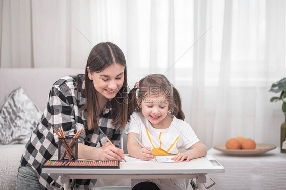 一位带着孩子的母亲坐在桌旁做作业孩子在家在家上学图片