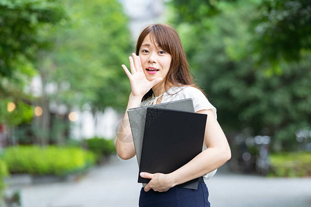 亚洲女商人用手捂着嘴摆姿势吸引注意力图片