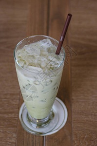 木桌上玻璃杯中的冰绿茶背景图片