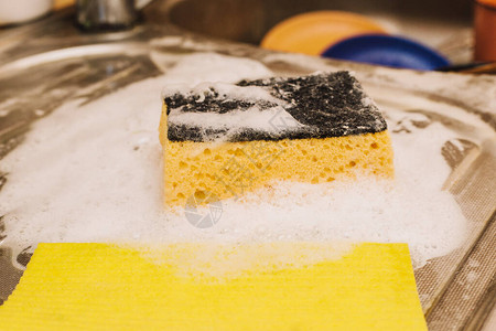 黄色海绵和洗碗液肥皂在肮脏的水槽上装满了盘图片