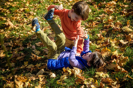 两个男孩在户外打架在夏天公园摔跤的朋友兄妹之间的较量好斗的孩子把小男孩抱在地背景图片