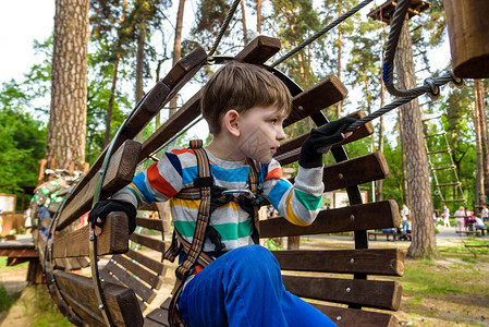 快乐的孩子克服了绳索冒险公园的障碍暑假概念小男孩在绳索冒险公园玩耍现代儿童游乐图片
