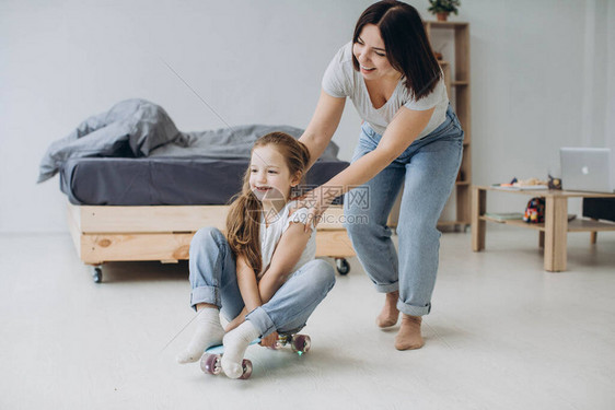 妈带着学龄前女儿在客厅玩滑板图片