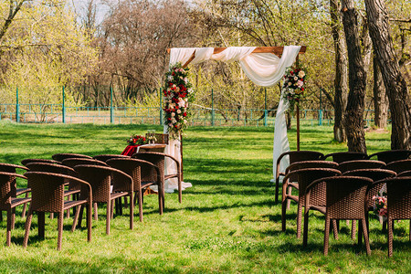 Wooden婚礼拱门装饰着红白鲜花户外结婚仪式婚图片
