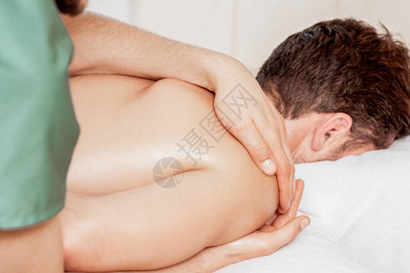 近身按摩治疗师的手在温泉疗养场对男人肩图片