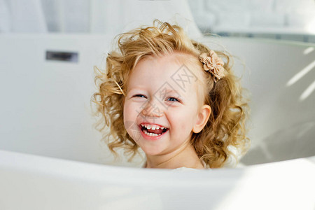 带着金发的小女孩笑着坐在浴室里玩孩子们的恶作剧和游戏背景图片