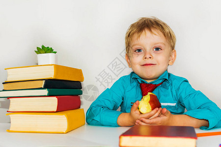 在书桌的学龄前男孩吃苹果图片
