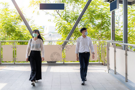 两名亚洲男女在步行或走天行道的每个人之间保持两米或六英尺的距离图片