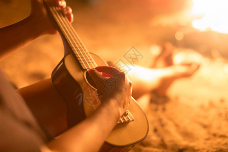 一位女音乐家在外面弹吉他坐在火图片