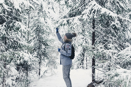 灰色帽子和一件蓝色夹克与白色靴子在美丽的冬季景观的背景上的女孩卡图片